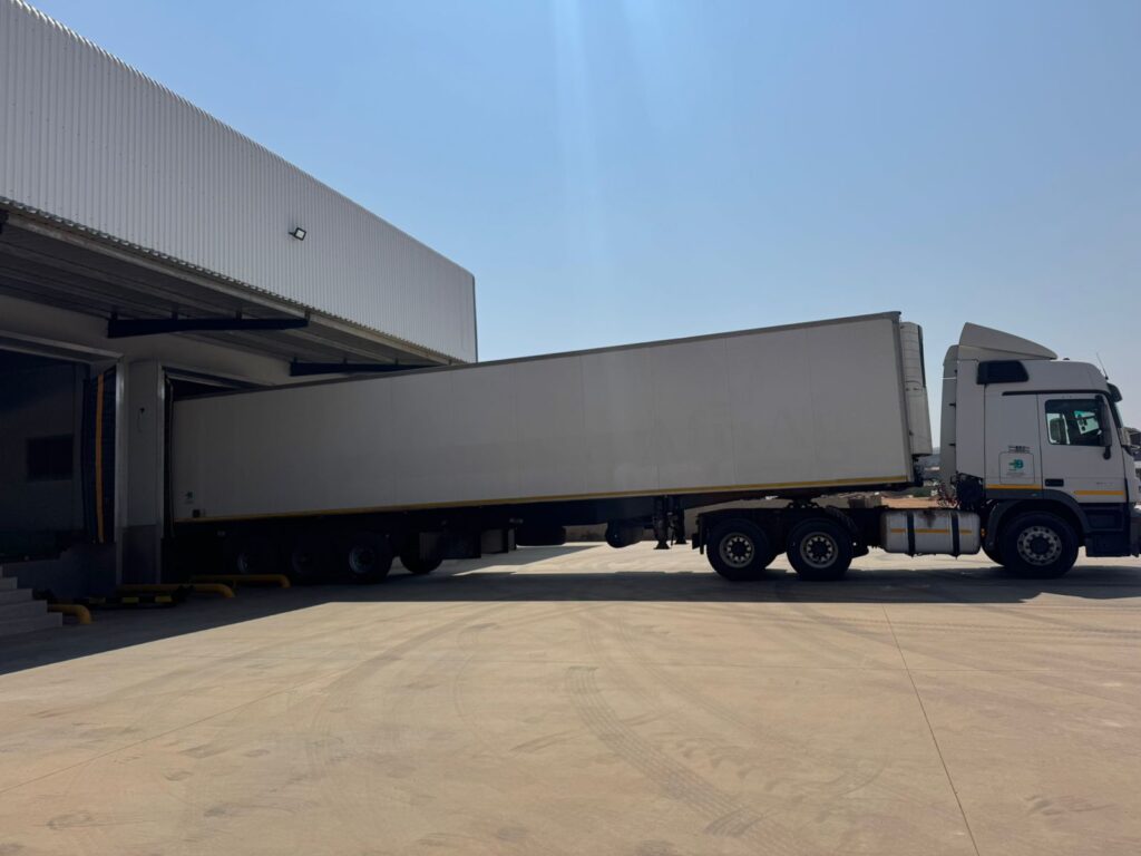 Large refrigerated truck reversing into a loading dock at Plus Zero’s facility, demonstrating efficient and professional refrigerated transport services in Aston Manor for cold chain logistics.